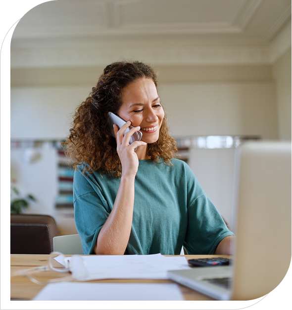 Smiling woman on phone working at laptop